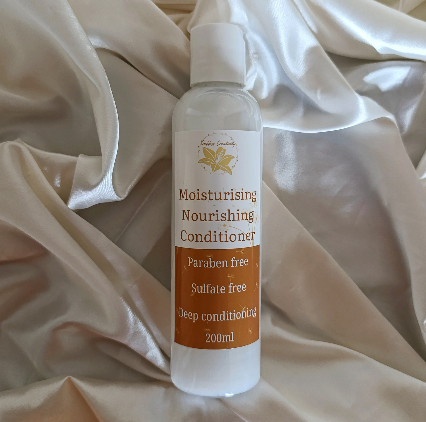 Goddess Creativity Moisturising Nourishing Conditioner– paraben-free, sulfate-free, and colourant-free formula for deep 4c hair conditioning in a 200ml clear bottle, photographed on silky cream fabric.